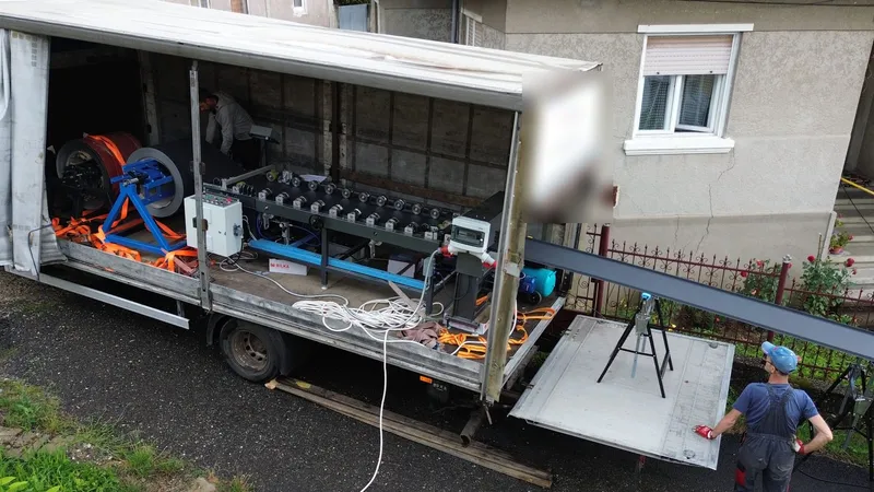 Linia de profilare montată în camion, cu bobinele de tablă și rolele de profilare; un panou Linea Click iese pe spate, pe o capră.
